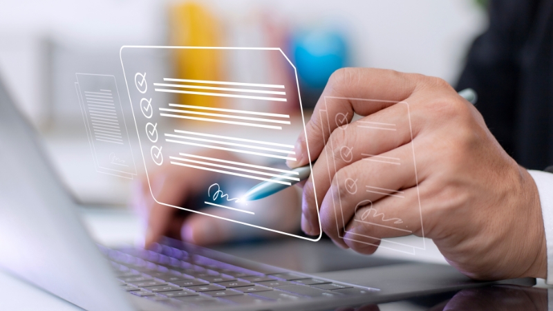 Ruka osobe koja koristi digitalni potpis na laptopu, uz grafički prikaz elektronskog dokumenta i potpisa na ekranu