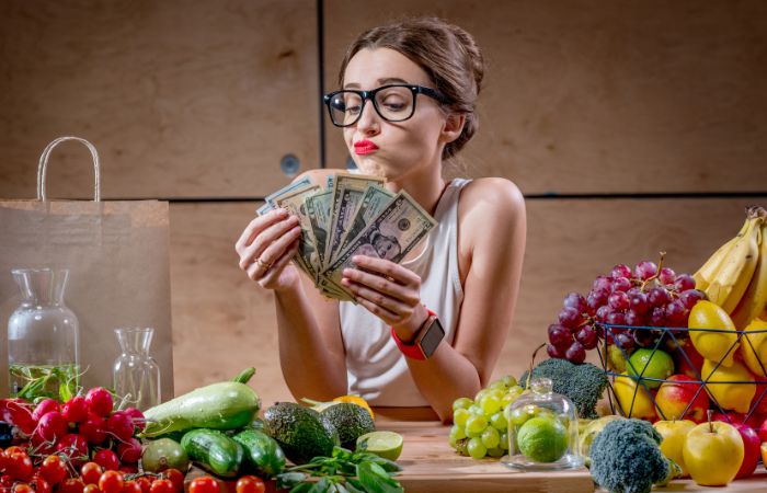 Zaposlena žena pored obroka drži novac kao naknadu za topli obrok