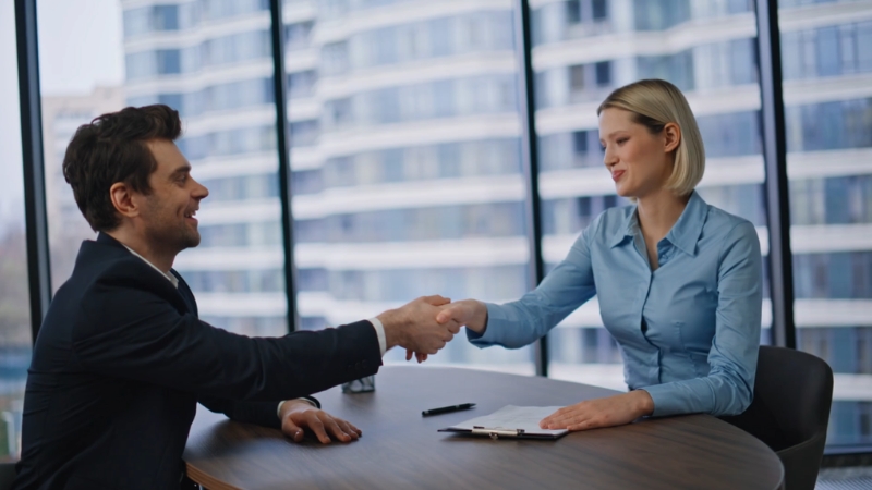 Čovek i žena se rukuju u kancelariji, ilustrovajući temu da li paušalac može zaposliti radnika