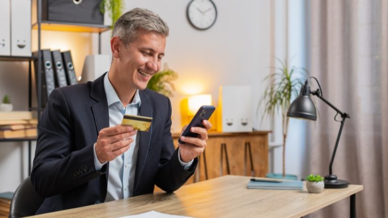 Preduzetnik koristi telefon i karticu dok prebacuje novac sa poslovnog na lični račun