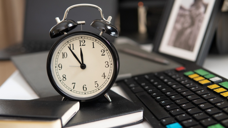 Sat na radnom stolu pored tastature simbolizuje rad na pola radnog vremena