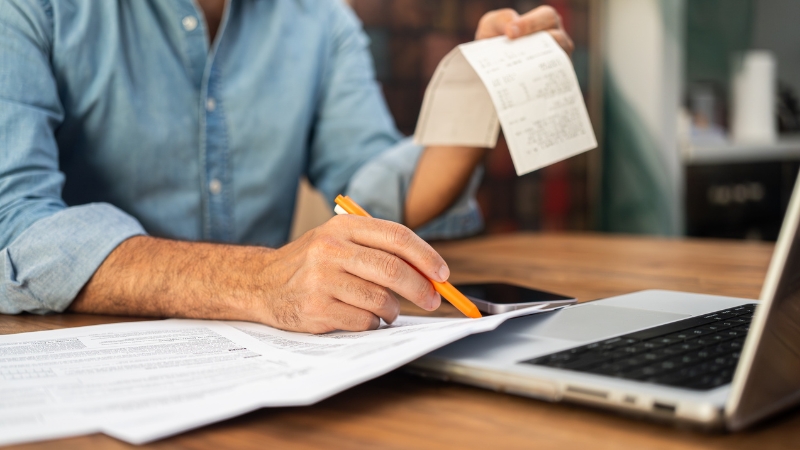 Osoba proverava fiskalni račun i beleži podatke kako bi uočila grešku