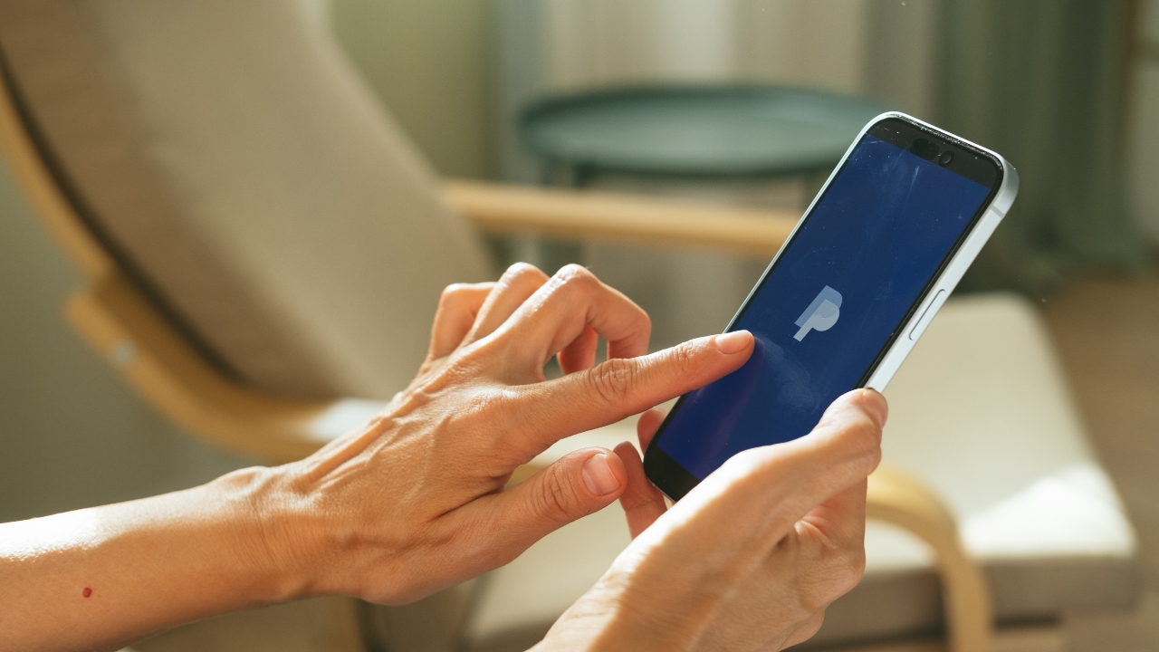 Ruka drži telefon sa otvorenom PayPal aplikacijom
