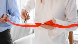 Osoba seče crvenu traku na otvaranju nove firme