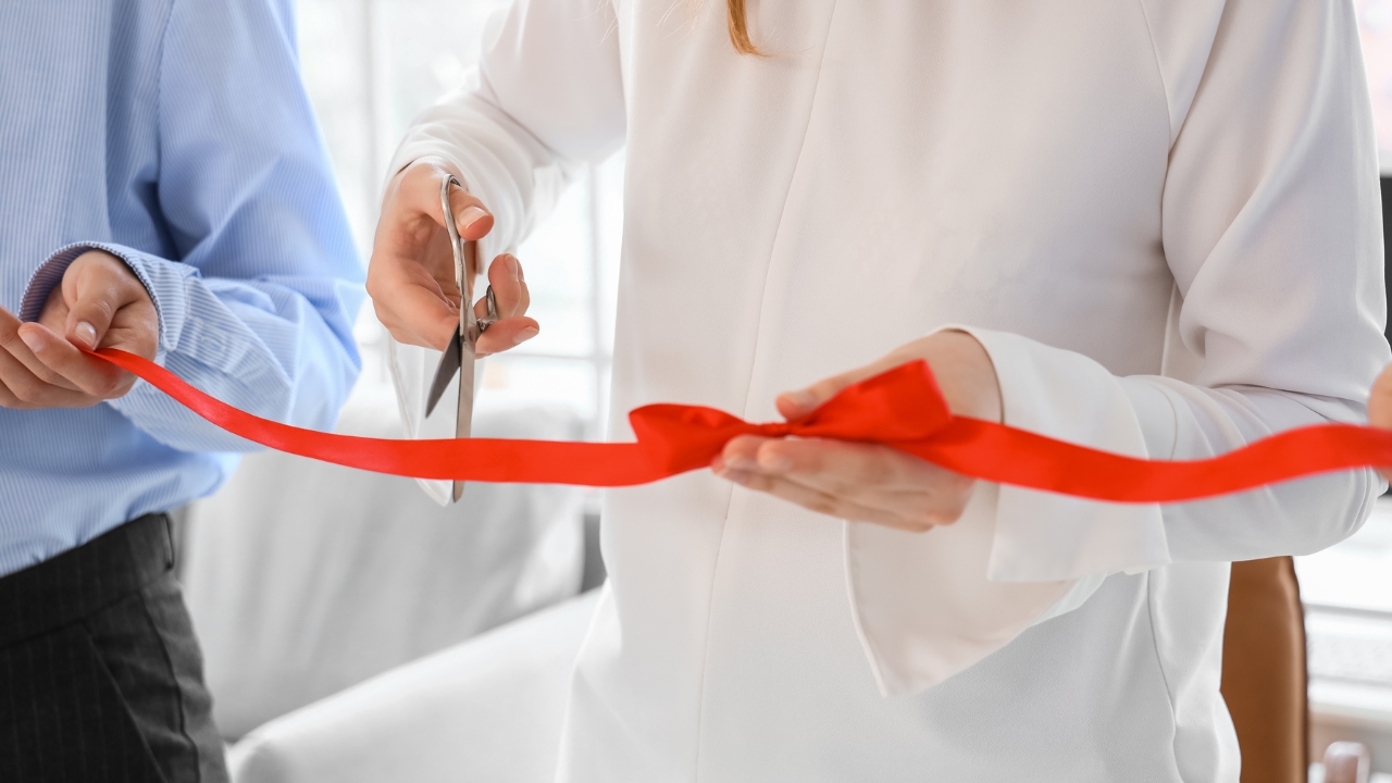Osoba seče crvenu traku na otvaranju nove firme