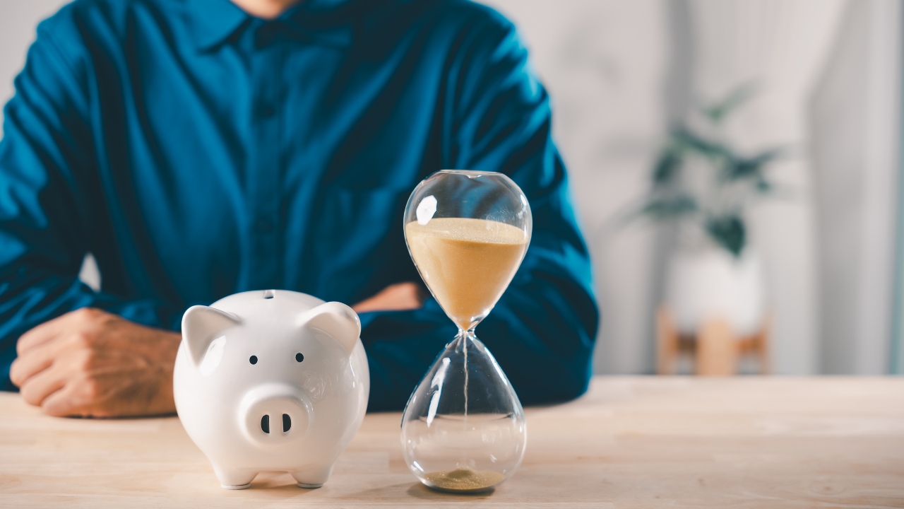 Kasa za štednju i peščani sat ispred osobe kao simbol vremena i troškova