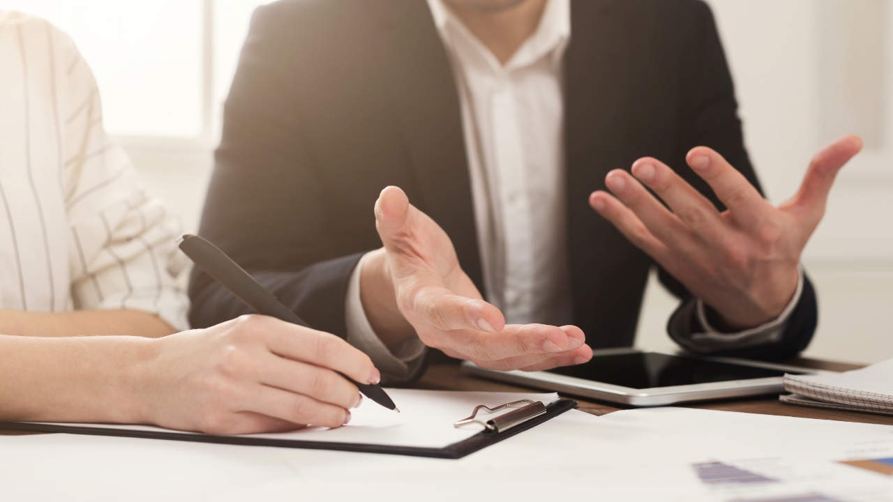 Osoba potpisuje dokument dok druga objašnjava detalje oko otvaranja firme