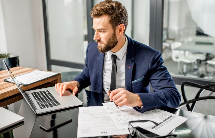 Čovek u kancelariji proverava izvod iz banke na laptopu