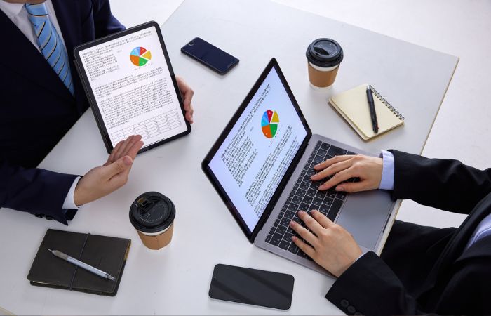 Loro doznaka – dva zaposlena pregledaju podatke na laptopu i tabletu